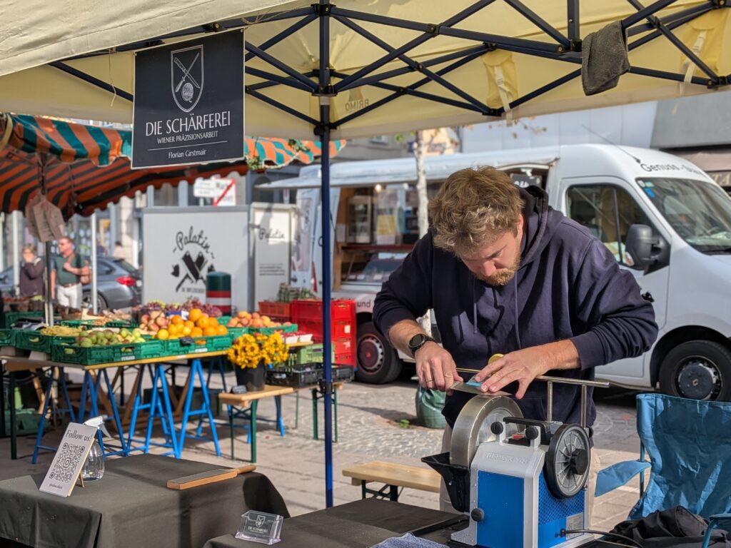 Messerschleifen auf dem Tormek am Marktstand am Rochusmarkt der Schärferei in Wien